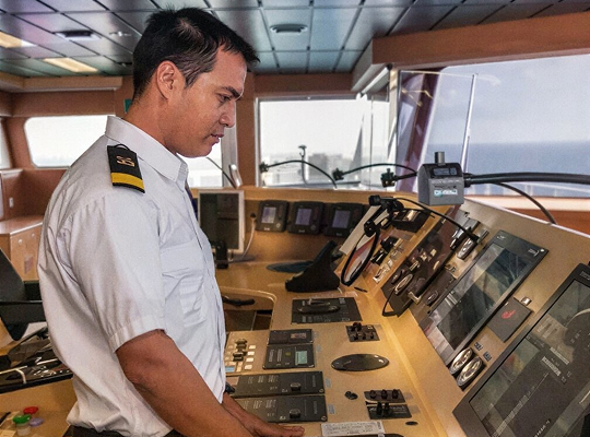 Tripulante operando a ponte de comando de um navio